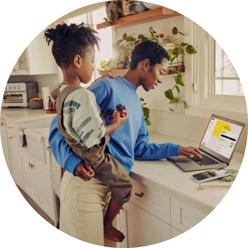 image of a user carrying their kids while using EarnIn web application on a laptop